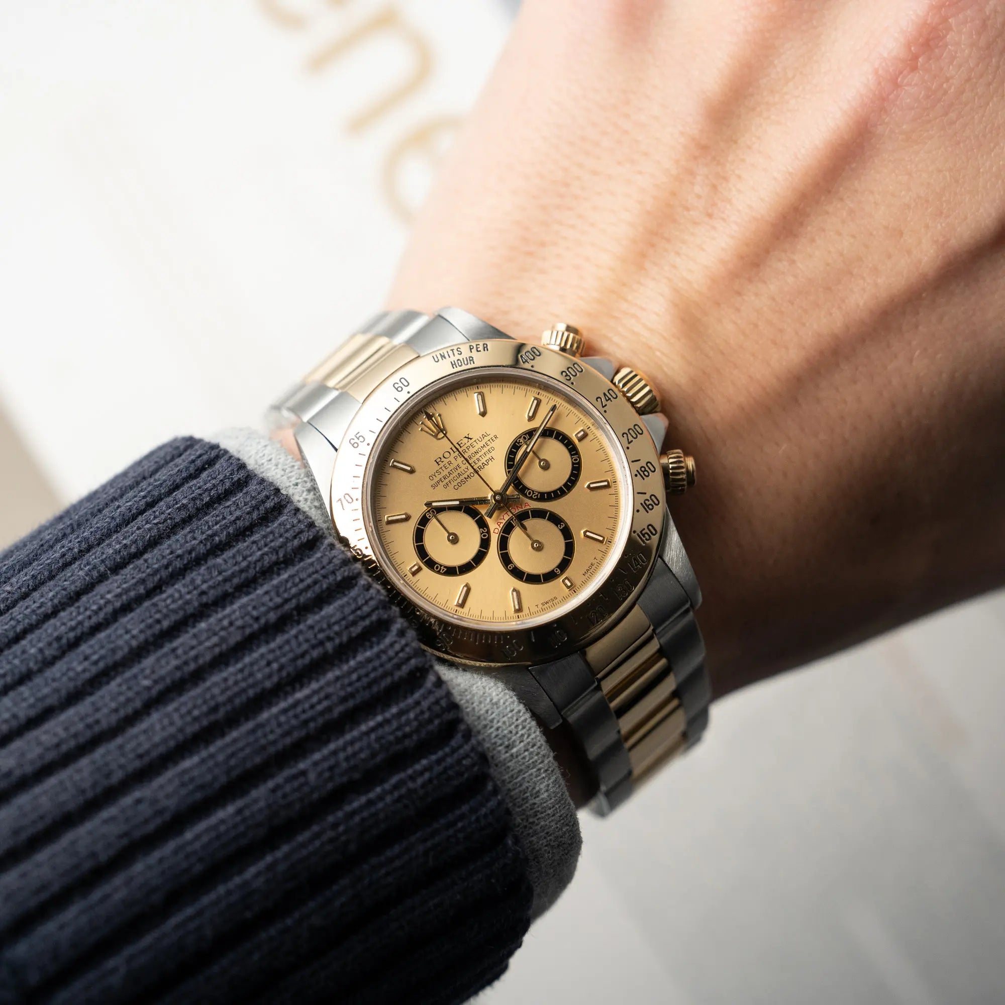 Mann trägt die Rolex Zenith Daytona in Stahl-Gold mit goldfarbenem Zifferblatt an seinem Handgelenk und präsentiert die Armbanduhr in die Kamera