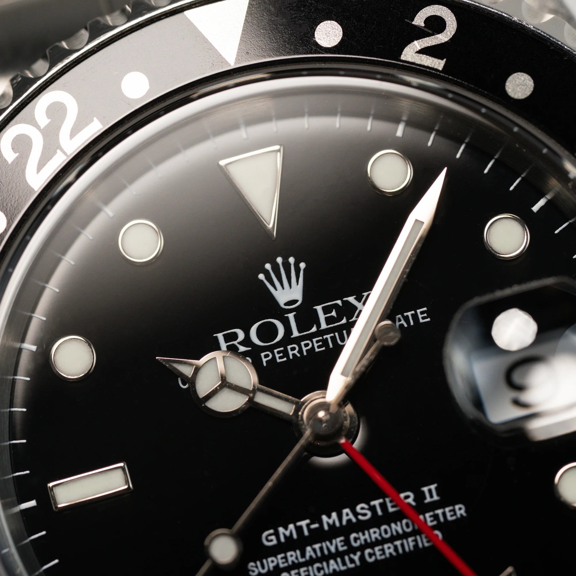 Makroaufnahme des Zifferblatts und der Lünette derSeitliches Gehäuse der Rolex GMT Master 2 (Referenz 16710) mit der Coke-Lünette in schwarz-rot
