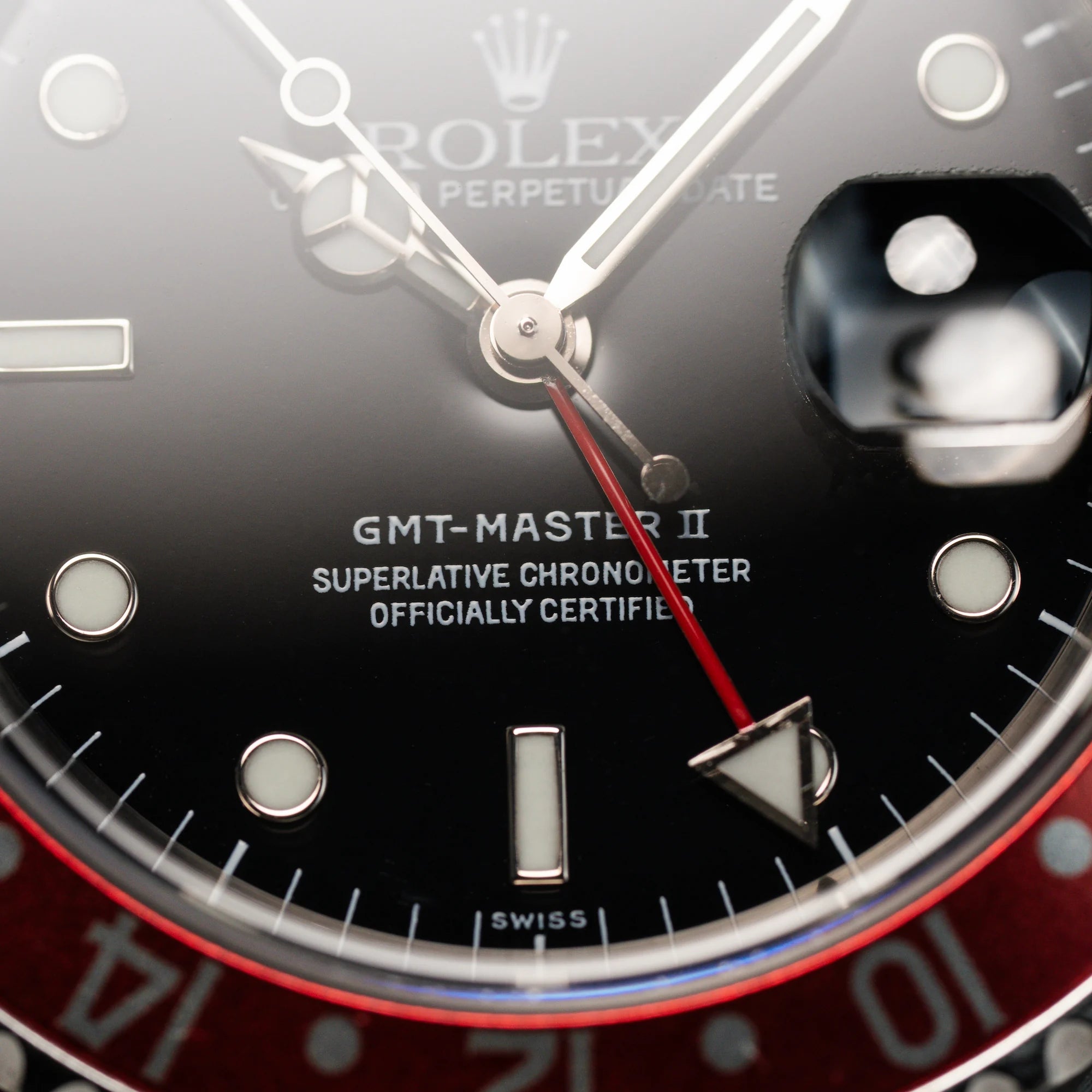 Makroaufnahme des Zifferblatts und der Lünette derSeitliches Gehäuse der Rolex GMT Master 2 (Referenz 16710) mit der Coke-Lünette in schwarz-rot mit dem "swiss only" Zifferblatt