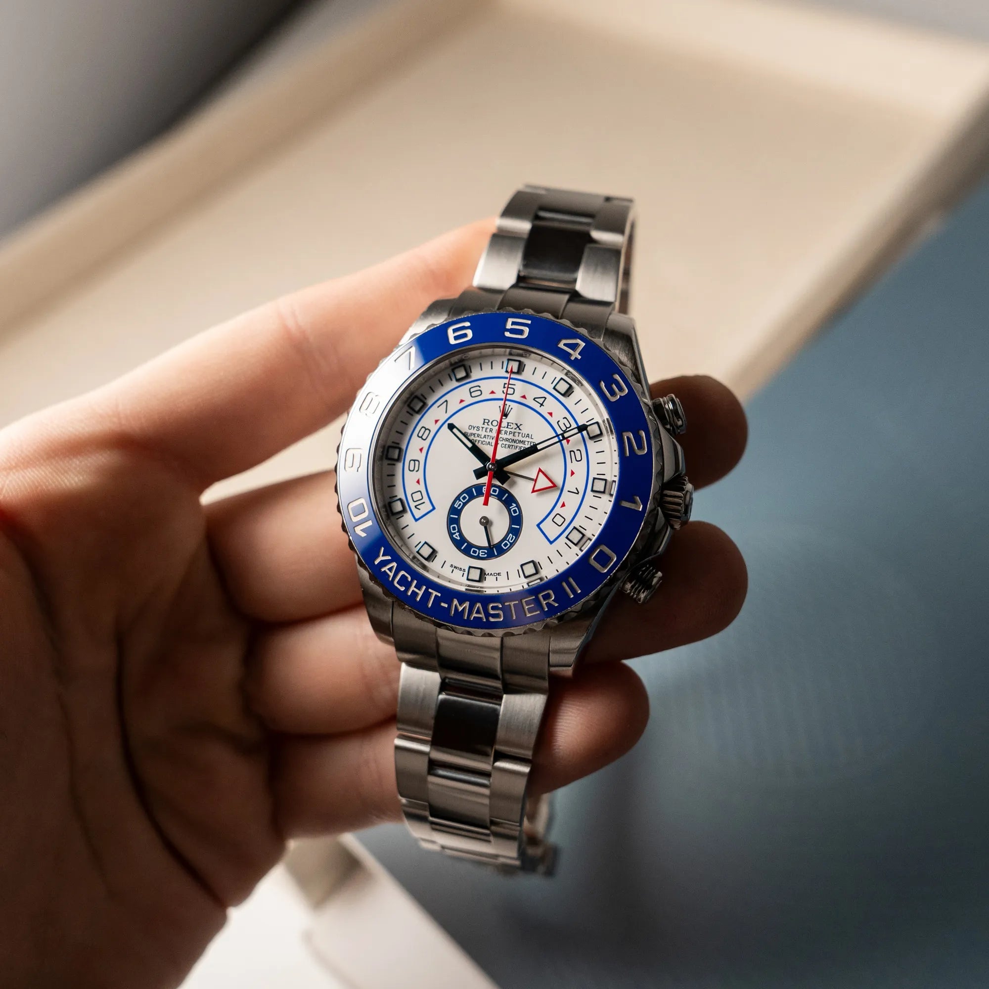Mann hält die Rolex Yacht-Master 2 mit weißem Zifferblatt und blauer Lynette in seiner Hand und präsentiert die Uhr in die Kamera