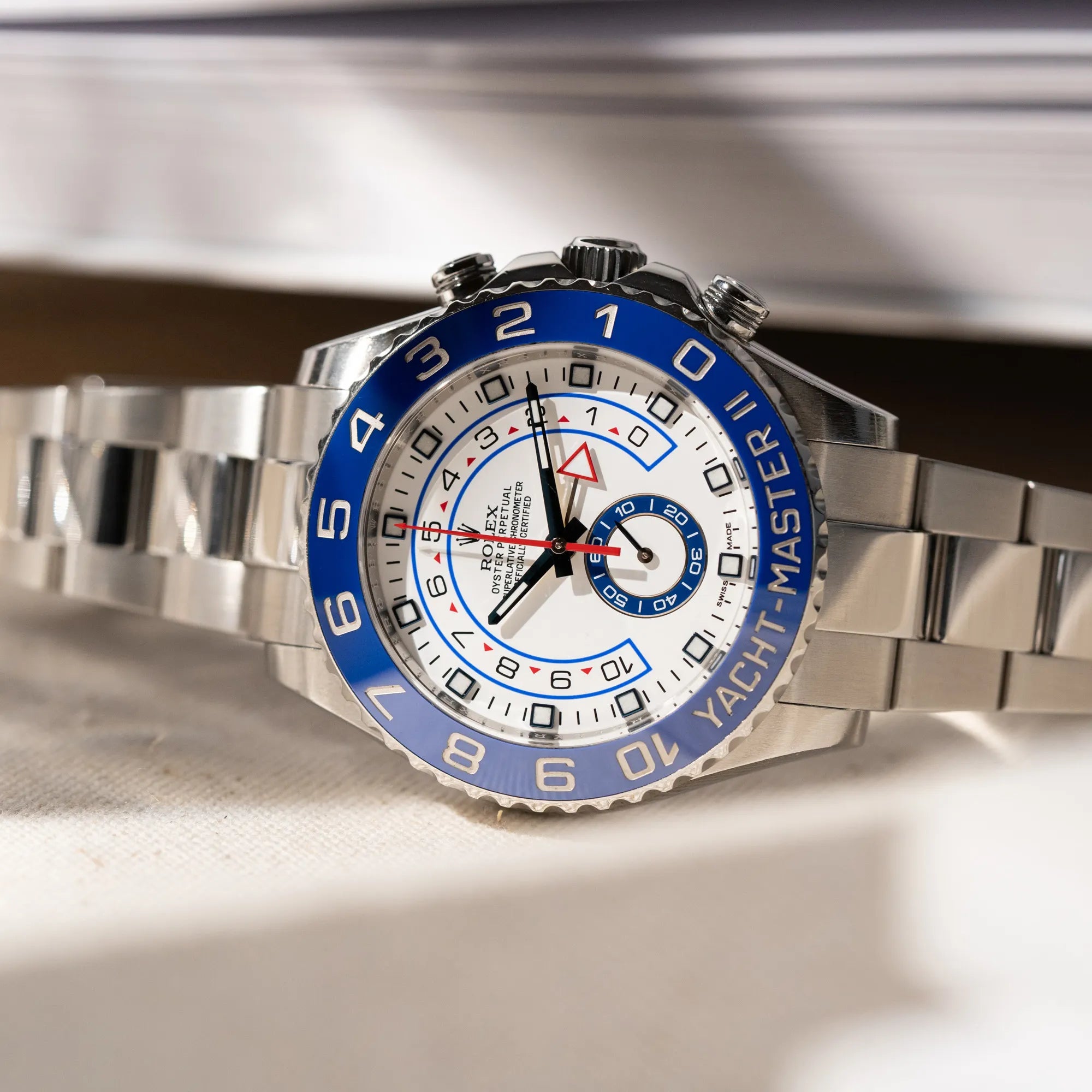 Detailaufnahme der seitlich auf dem Gehäuse liegenden Rolex Yacht-Master 2 mit weißem Zifferblatt und blauer Lynette