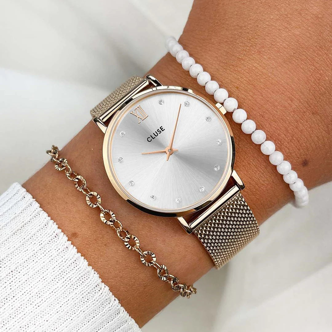 Frau trägt die Cluse Stahl-Uhr "Minuit Mesh" in roségoldener Farbe mit einem silbernen Diamant-Zifferblatt an Ihrem Handgelenk