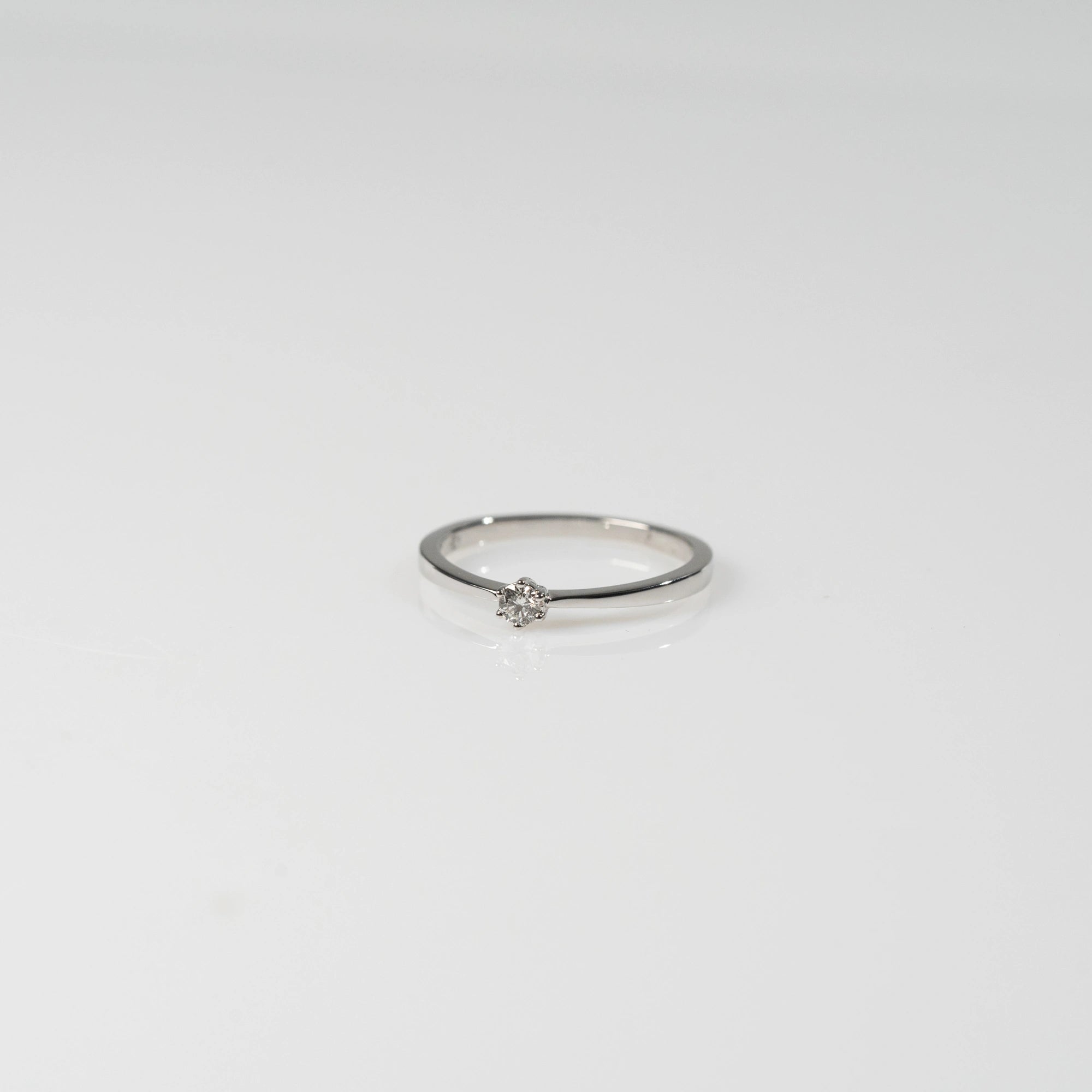 Produktfotografie des liegenden Weißgold-Verlobungsrings "Promise" aus der Schmuckatelier Lang Collection mit einem in einer 6er Kappe gefassten Diamanten