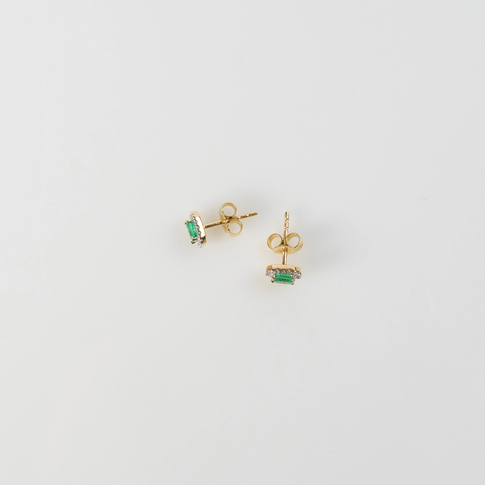 Draufsicht auf die aus Gelbgold gefertigten Smaragd-Brillant-Ohrstecker aus der Schmuckatelier Lang Collection, bei denen der zentrale, kräftig grüne Smaragd durch einen Diamantkranz eingerahmt ist - Foto zeigt den Verschlussmechanismus der Ohrstecker