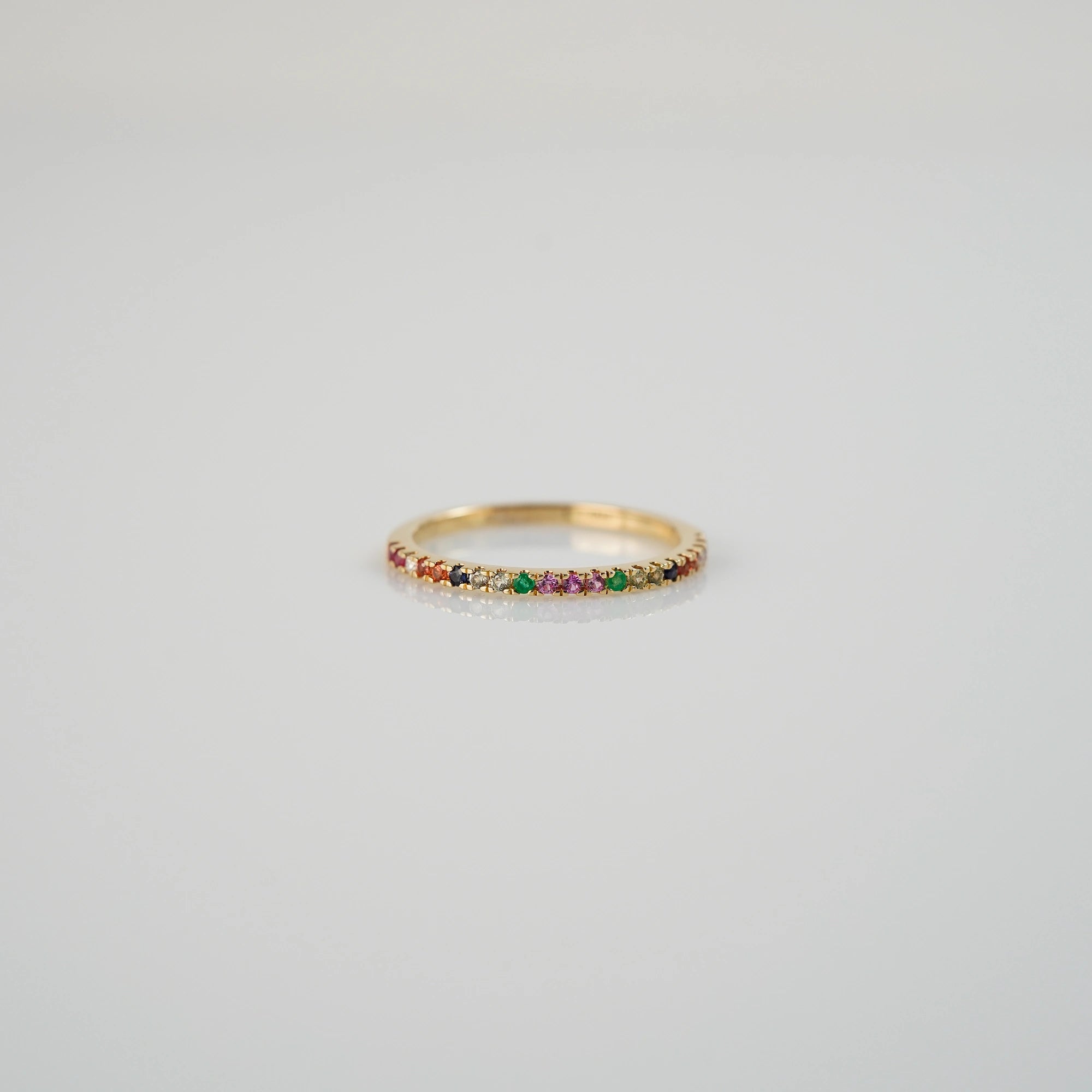 Produktfoto des liegenden Memoire-Rings mit einem Rainbow-Setting aus verschiedenen Edelsteinen mit einem bunten Farbspiel