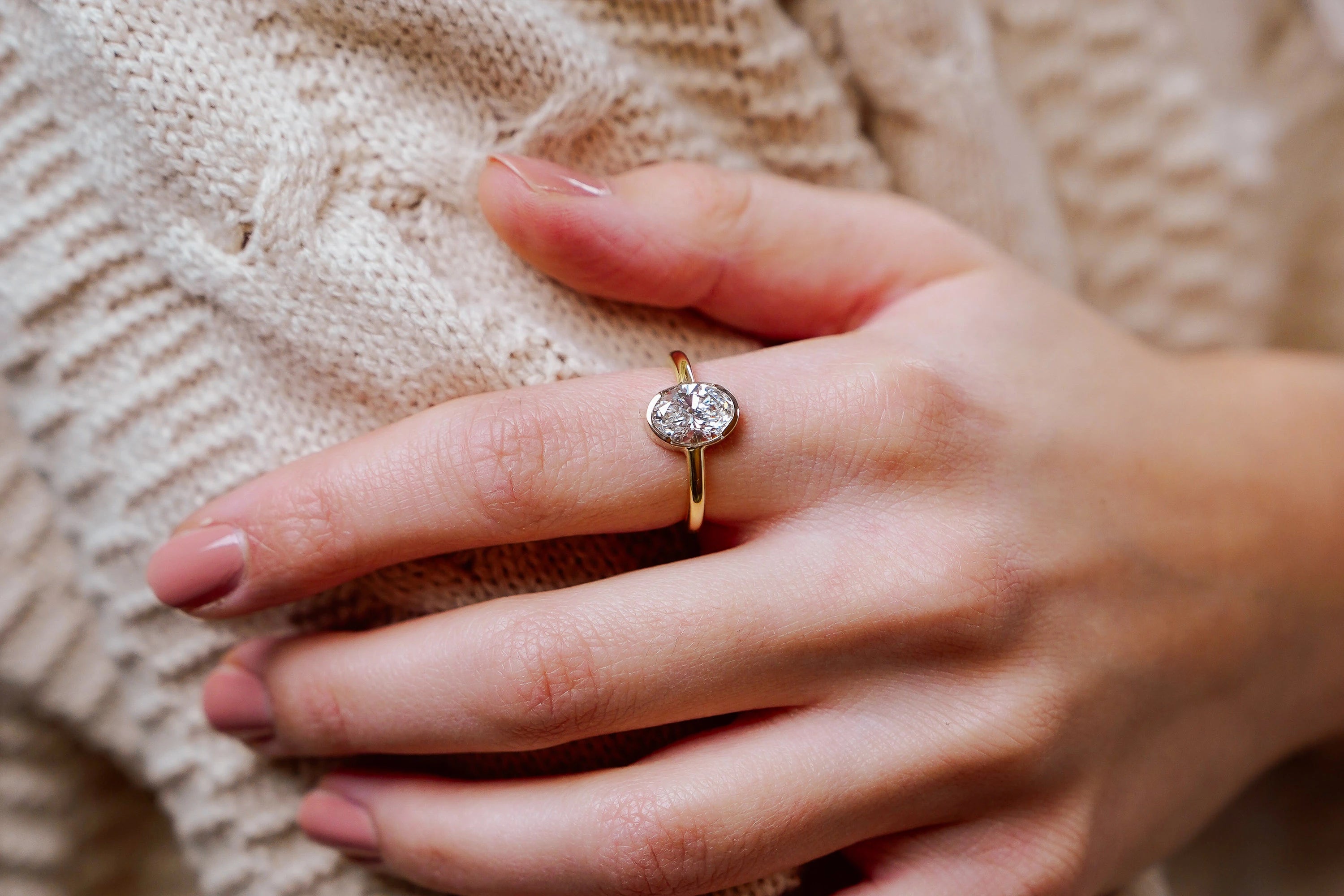 Frau präsentiert am Ihrem Zeigefinger den goldenen Verlobungsring "Gleaming Love" aus der Schmuckatelier Lang Collection mit einem 2,05ct Labor-Diamanten als Highlight