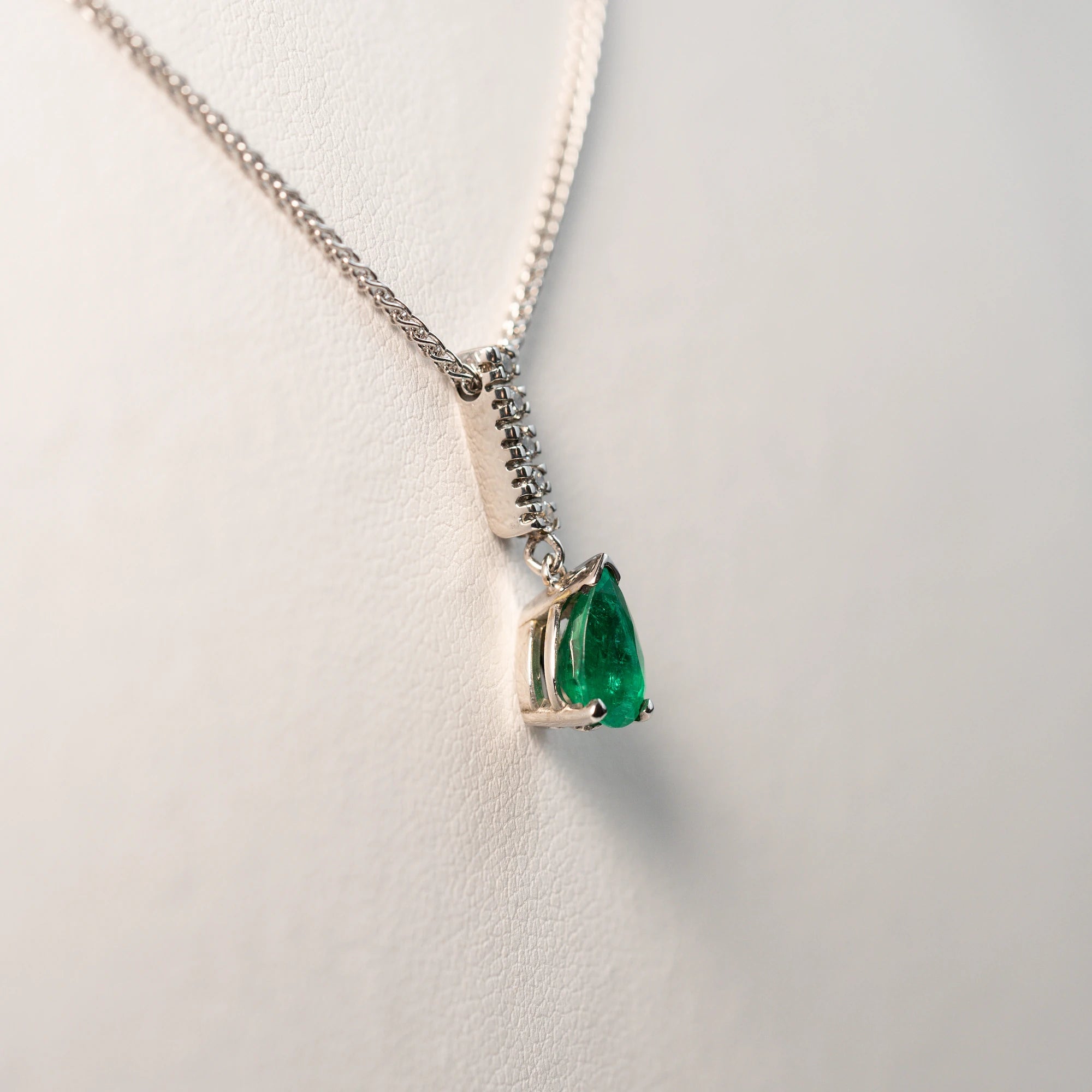 Seitlicher Blick auf den Anhäger, bestehend aus einem Diamant-Steg und einem kräftigen, grünem Smaragd im Tropfenschliff