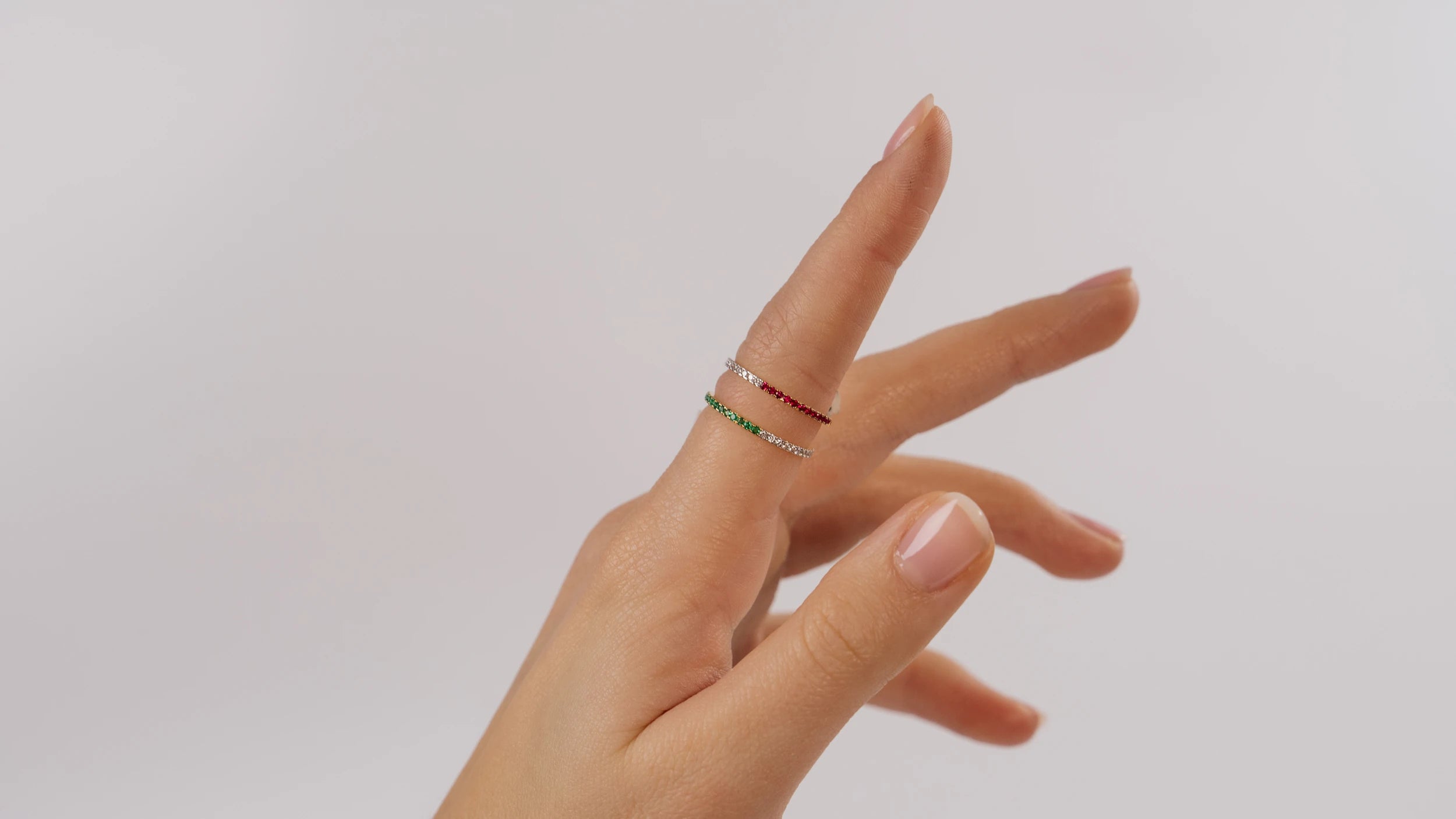 Frau trägt zwei Ringe aus der Schmuckatelier Lang Collection an Ihrem Zeigefinger: den Smaragd-Brillant-Ring und den Rubin-Brillant-Ring