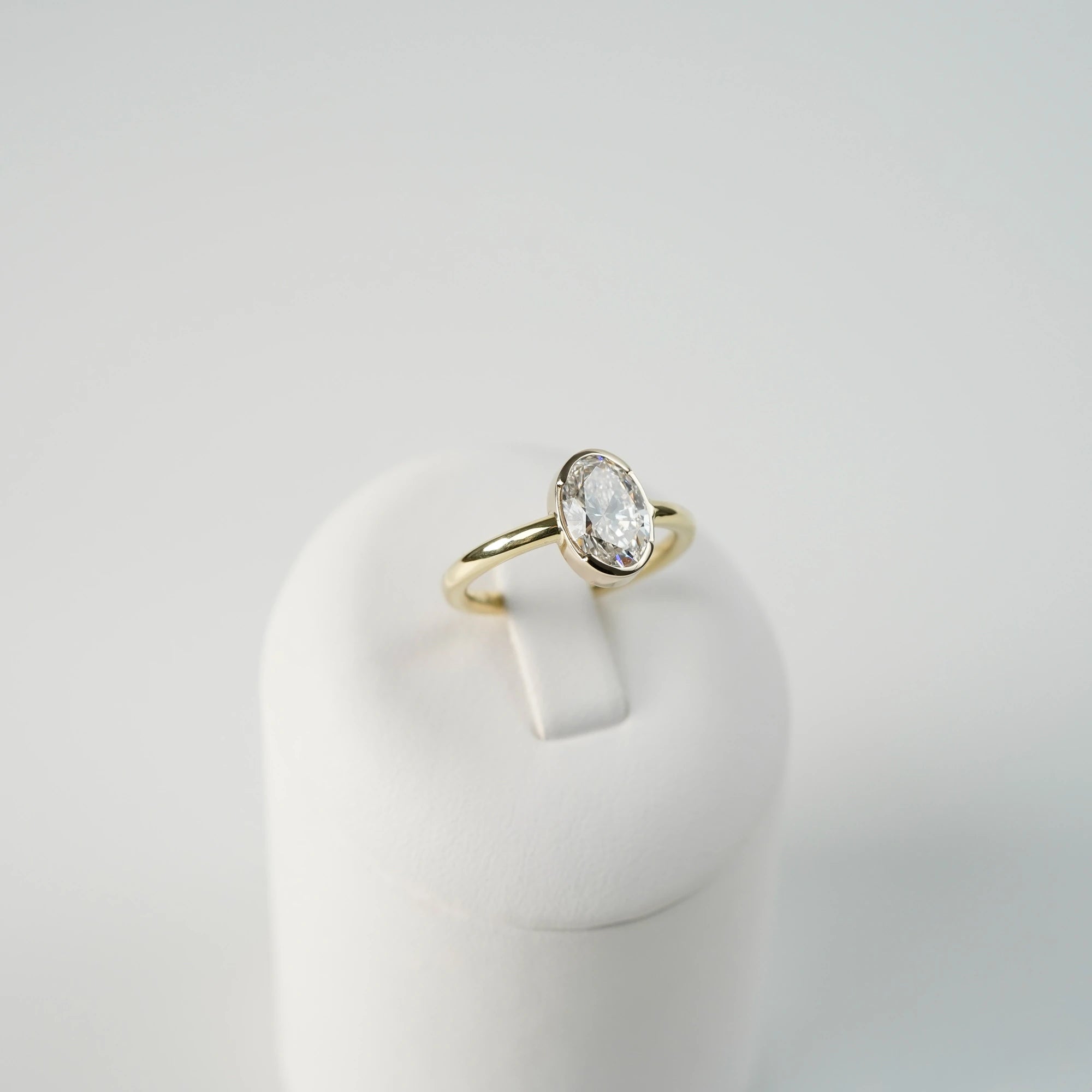 Produktfoto des in Gelbgold gefertigten Verlobungsring "Gleaming Love" mit einem großen Labor-Diamanten mit 2.03ct, während der Ring auf einem Ringständer steckt (leicht seitlicher Blickwinkel)