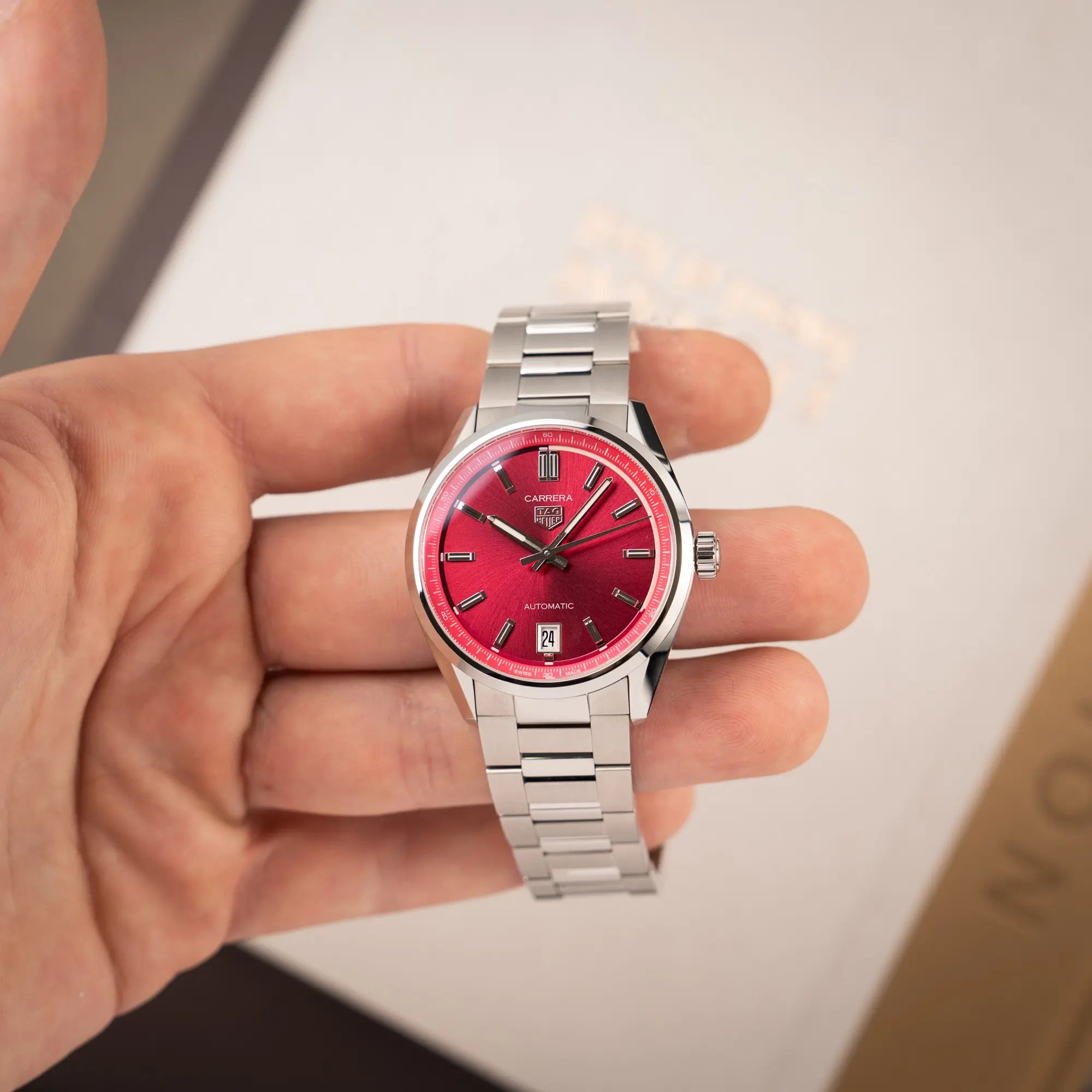 Mann präsentiert die Tag Heuer Carrera Date Lady mit einem 36mm-Gehäuse und einem markanten pinken Zifferblatt mit Sonnenschliff-Finish in die Kamera