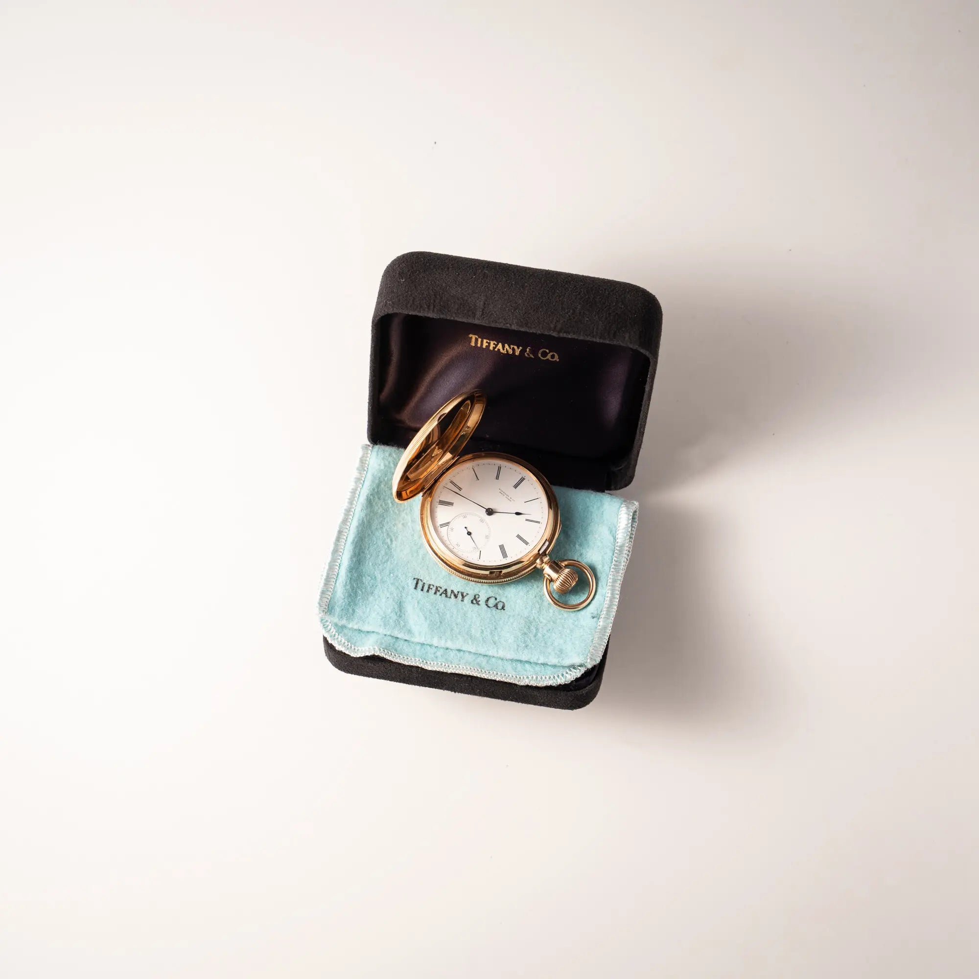 Tiffany & Co Savonette Taschenuhr aus 18k Gelbgold mit weißem Zifferblatt und römischen Indizes liegt in der Uhrenbox