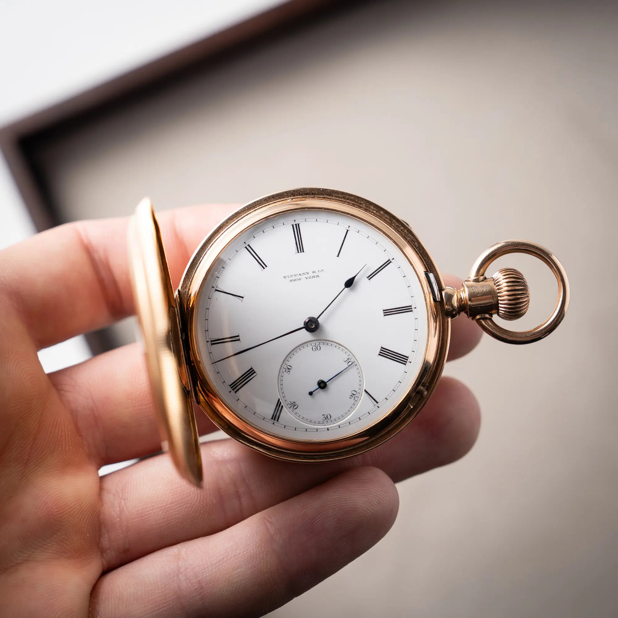 Mann präsentiert die Tiffany & Co Savonette Taschenuhr aus 18k Gelbgold mit weißem Zifferblatt und römischen Indizes