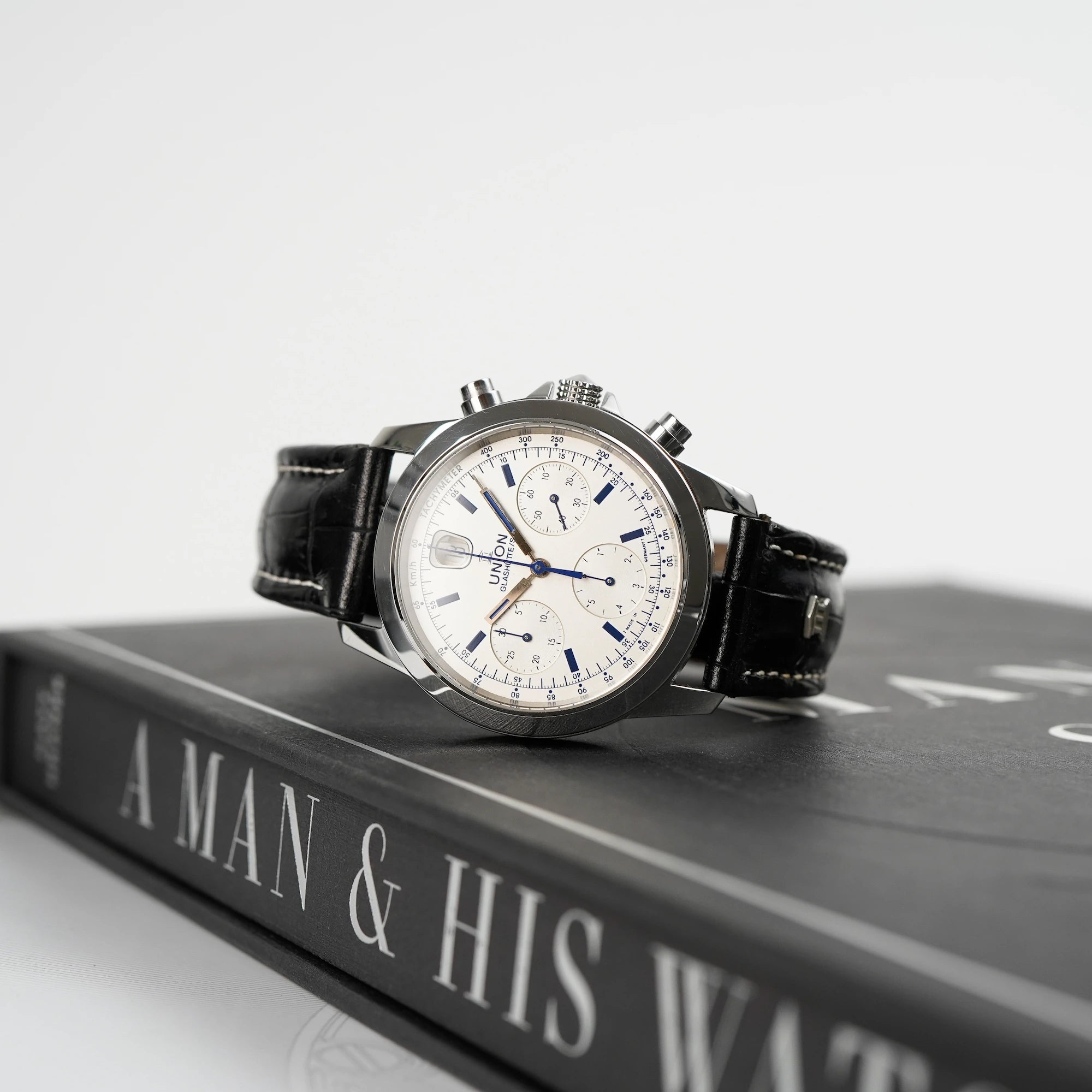 Tradition Chronograph von Union Glashütte mit weißem Zifferblatt liegt auf dem bekannten Uhrenbuch  "A Man & His Watch"