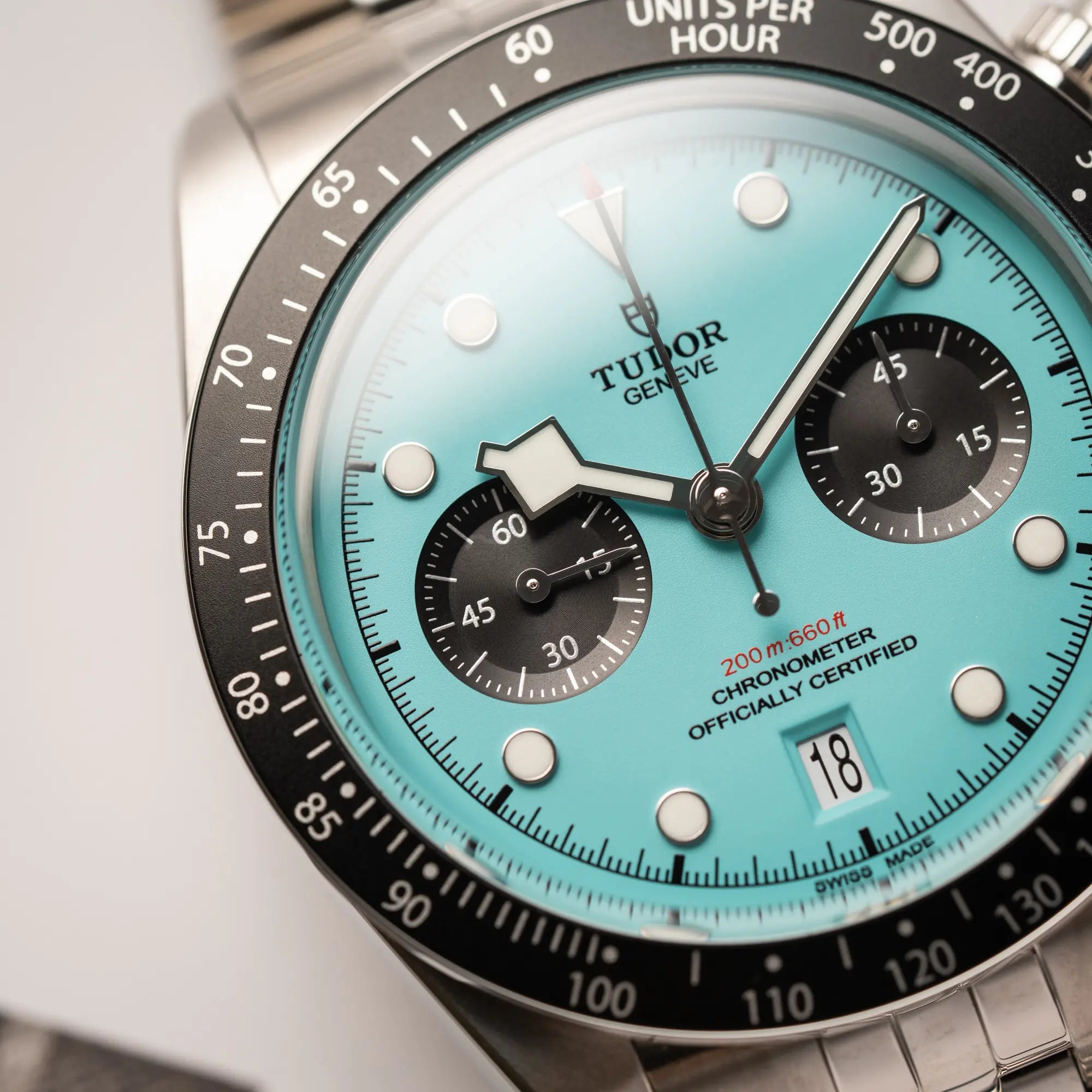 Nahaufnahme des Tudor Black Bay Chronograph Flamingo mit dem türkis-blauen Zifferblatt mit schwarzen Totalisatoren und schwarzer Lünette mit Zähler-Skala zeigt die Struktur des Zifferblatts und den Snow-Flake-Zeiger