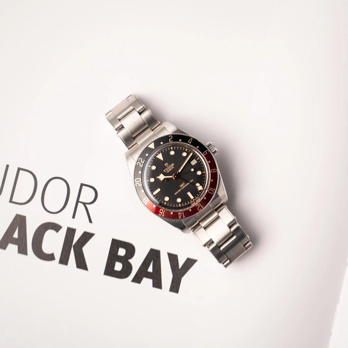Produktfotografie zeigt die Tudor BlackBay GMT Coke der Referenz 7939G1A0NRU mit der schwarz-roten Lünette und bronzefarbenen Details am Edelstahlarmband  aus der Vogelperspektive
