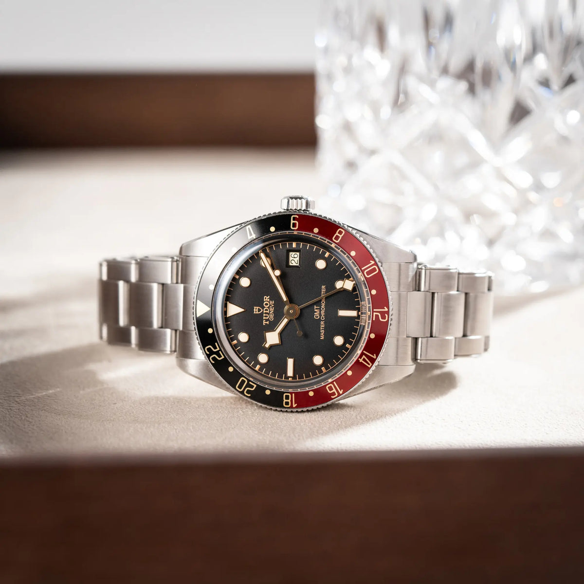 Produktfotografie der seitlich auf einem Juwelierstablet liegenden Tudor BlackBay GMT Coke der Referenz 7939G1A0NRU mit der schwarz-roten Lünette und bronzefarbenen Details am Edelstahlarmband 