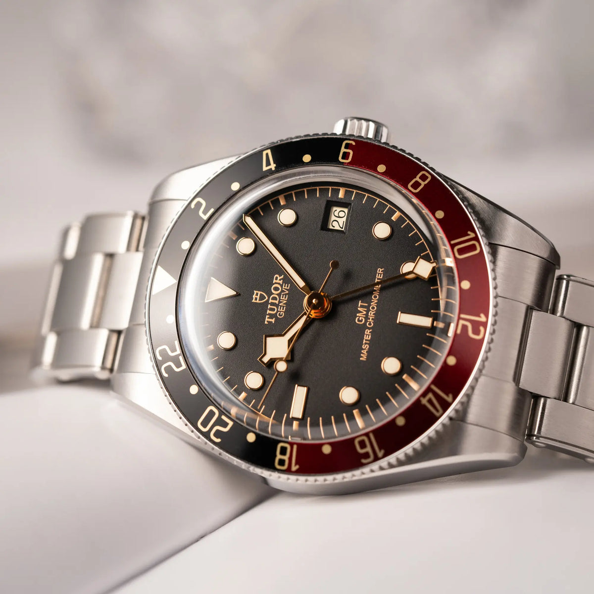 Nahe Produktfotografie der seitlich auf dem Uhrengehäuse liegenden Tudor BlackBay GMT Coke der Referenz 7939G1A0NRU mit der schwarz-roten Lünette und bronzefarbenen Details am Edelstahlarmband 