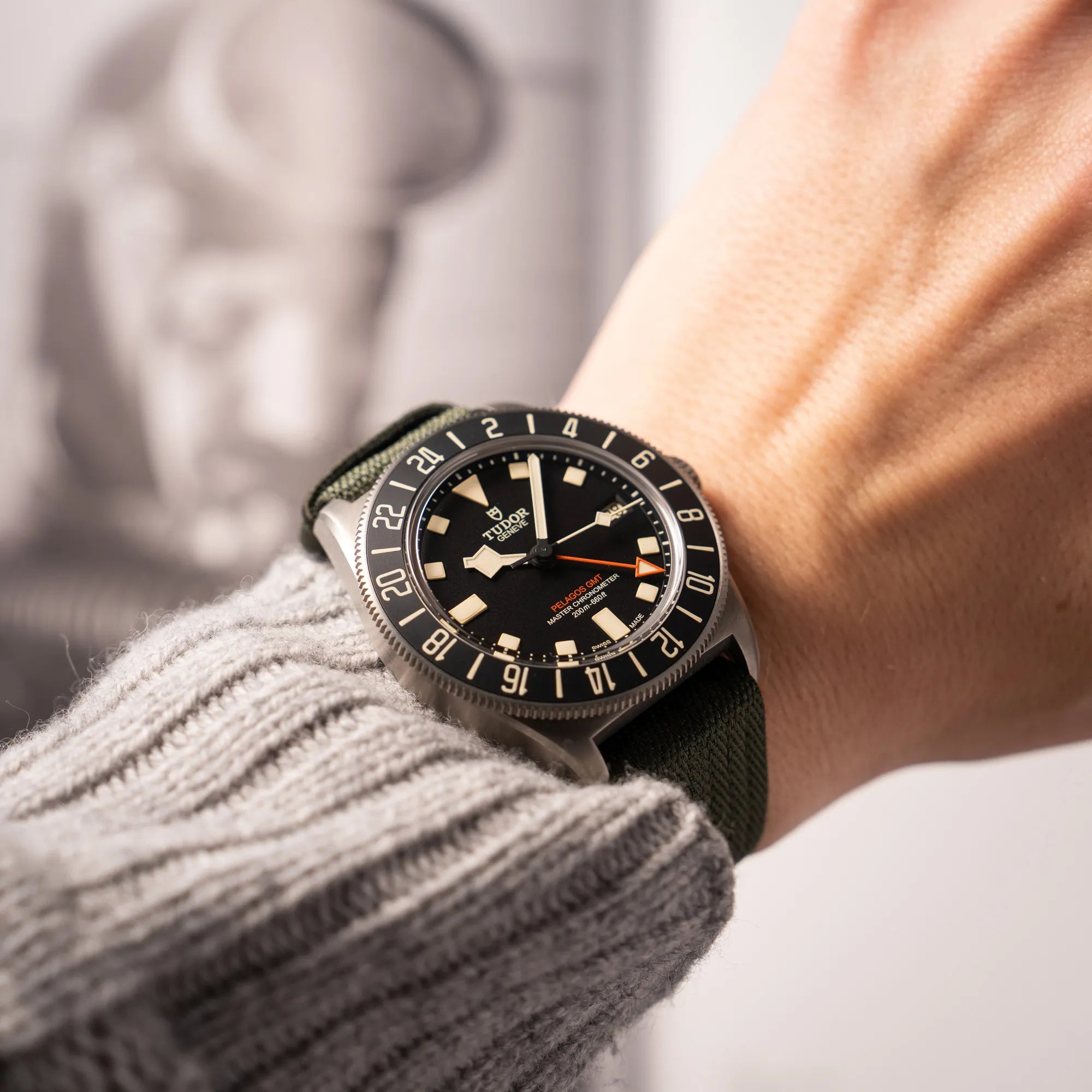 Mann trägt die Tudor Pelagos GMT Military der Referenz M2542G257NU-0002 mit Titan-Gehäuse und schwarzem Zifferblatt an einem olivgrünen Nato-Strap an seinem Handgelenk