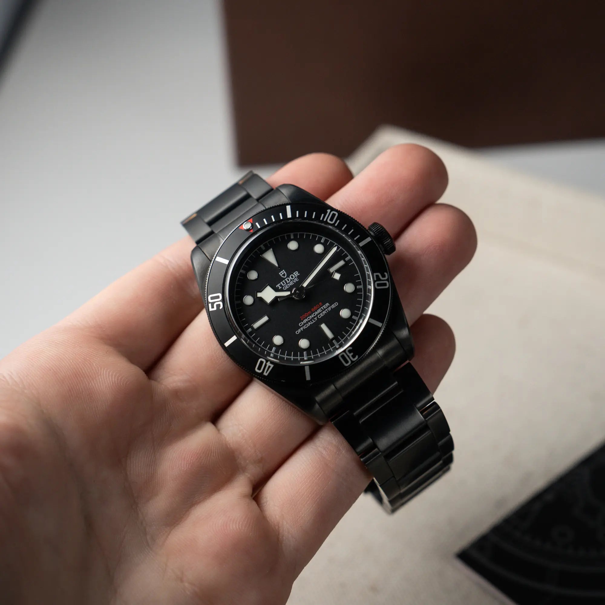 Mann hält die der Tudor Black Bay Dark 79230DK mit einem schwarz beschichteten Gehäuse und weißen Ziffern & Indizes in seiner Hand und präsentiert die Uhr