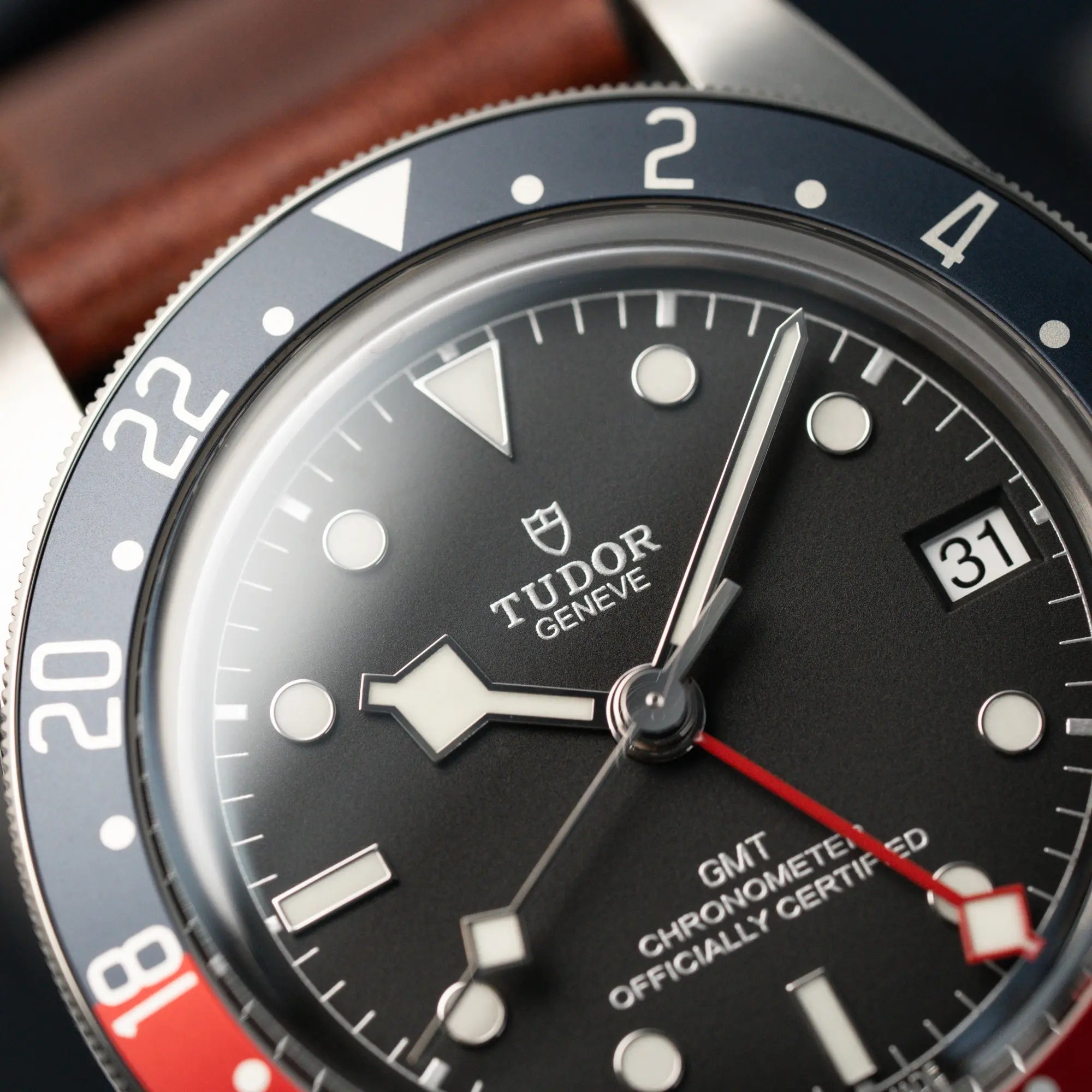 Detailaufnahme der Tudor Black Bay Pepsi mit der Referenz 97830RB am braunen Lederband im Neuzustand mit Fokus auf der oberen blauen Lünetten-Hälfte