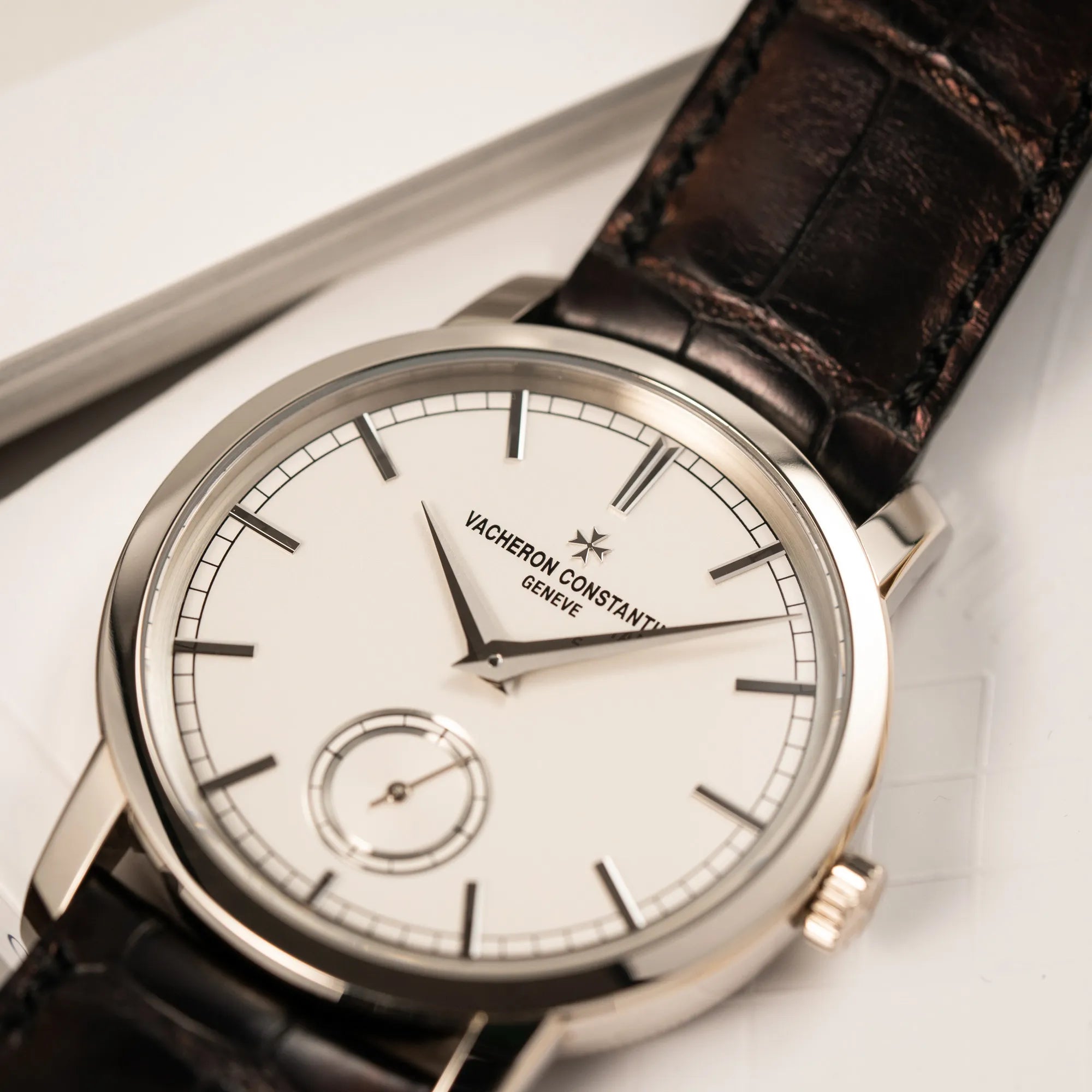 Detailaufnahme der Vacheron Constantin Traditionelle 82172 mit weißem Zifferblatt und einem Weißgold-Gehäuse am braunem Lederband mit Fokus auf dem "Vacheron Constantin Geneve" Schriftzug