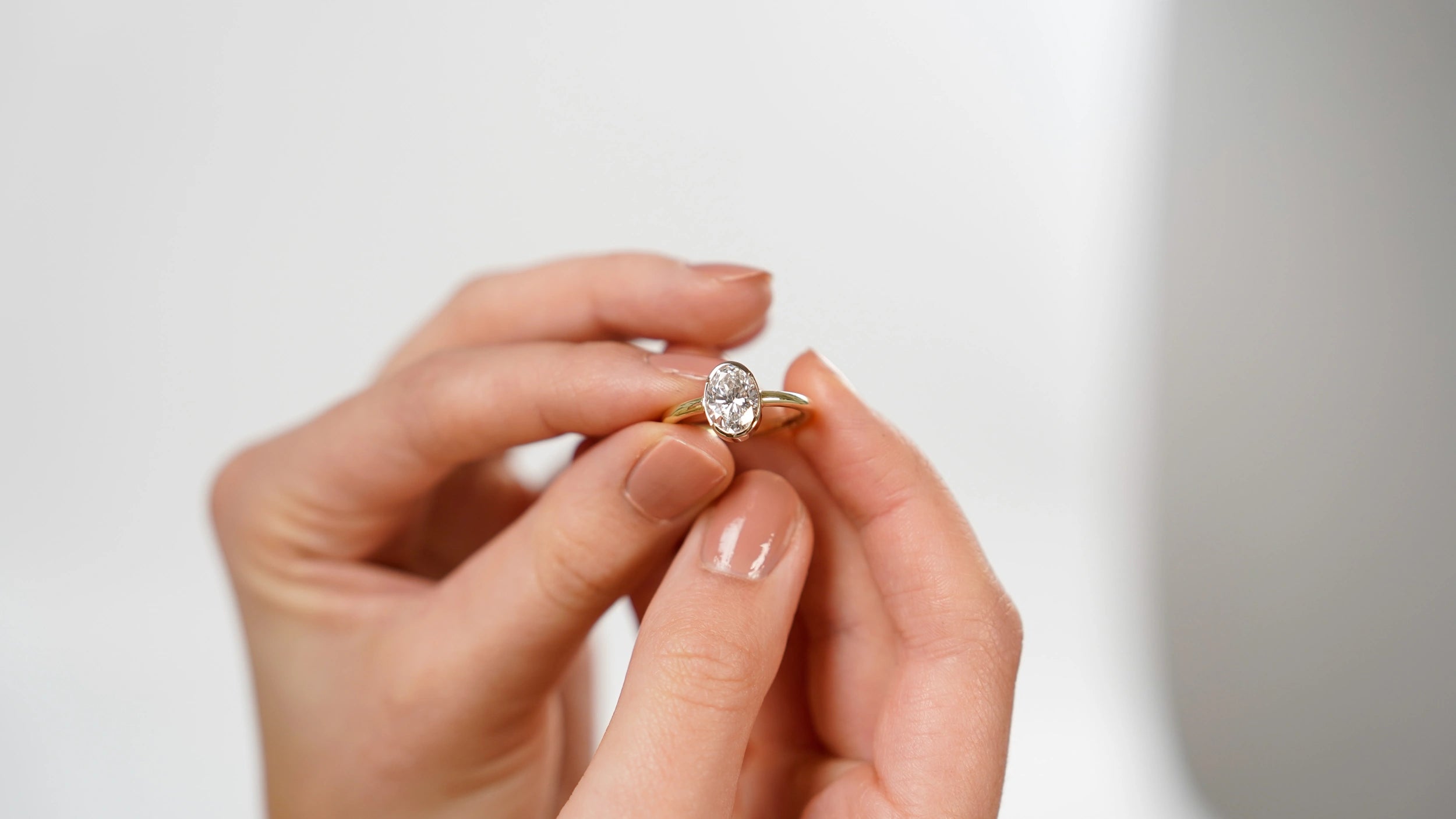 Frau hebt den Verlobungsring "Gleaming Love" in Gelbgold mit einem 2,03ct Labor-Diamanten aus der SL Collection in ihren Fingern