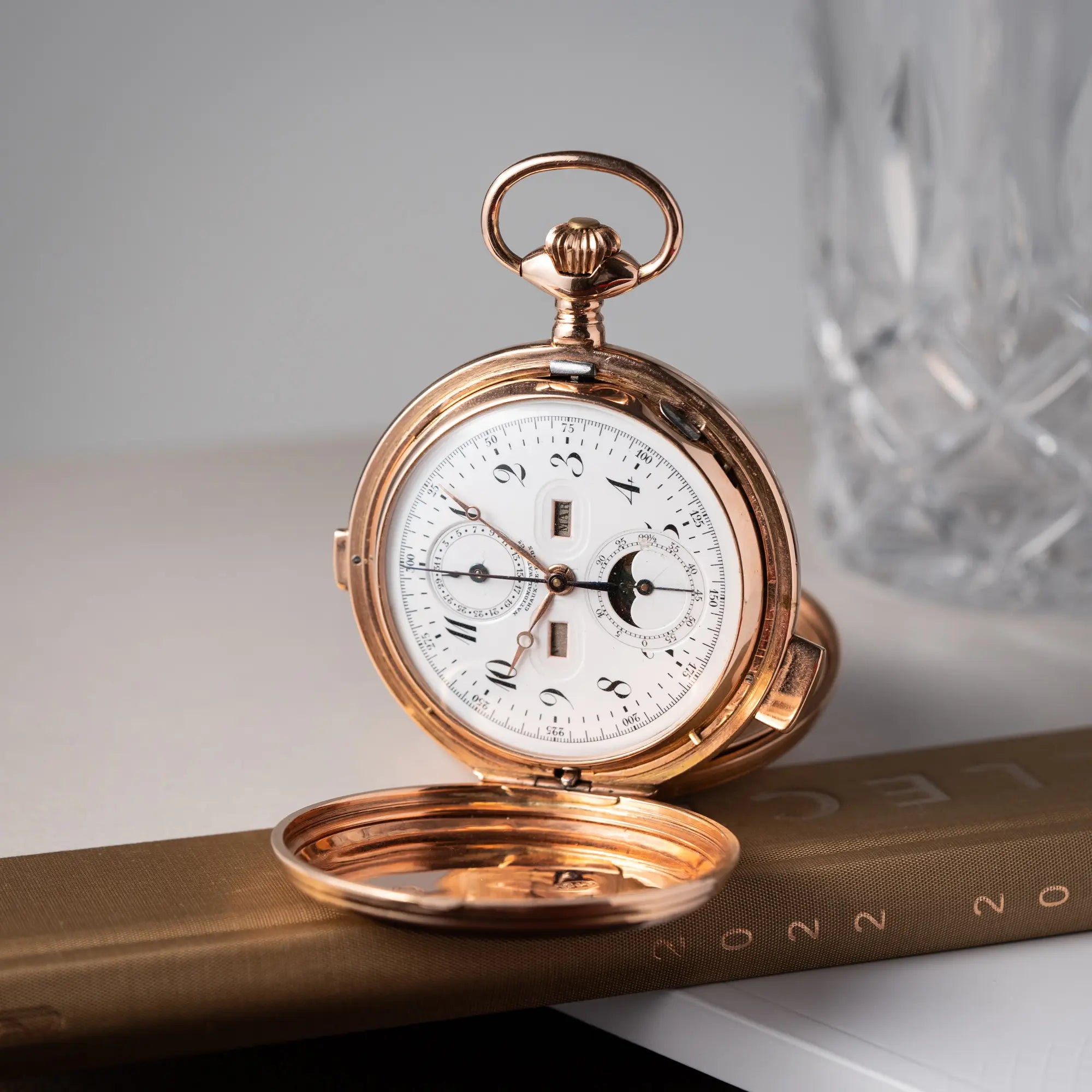 Produktfotografie von der Vollkalender Taschenuhr aus 14 Karat Roségold mit viertel Stunden Repetition und Mondphase-Anzeige bei 6 Uhr auf dem weißen Zifferblatt und arabischen Ziffern