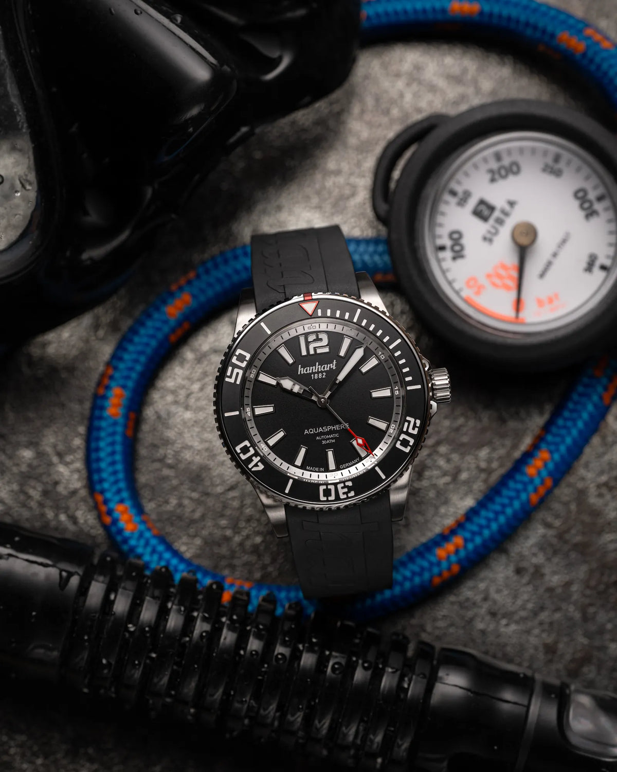 Produktfotografie der Hanhart Aquasphere Matte Black im 42mm-Edelstahl-Gehäuse am Edelstahlarmband mit schwarzem Zifferblatt und schwarzer Lünette zusammen mit Taucher-Equipment