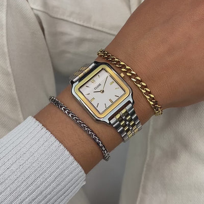 Frau trägt die Cluse Stahl-Uhr "Gracieuse" in Stahl-Gold-Optik (bicolor) mit weißem Zifferblatt an ihrem Handgelenk und präsentiert diese mit einem Wrist-Roll