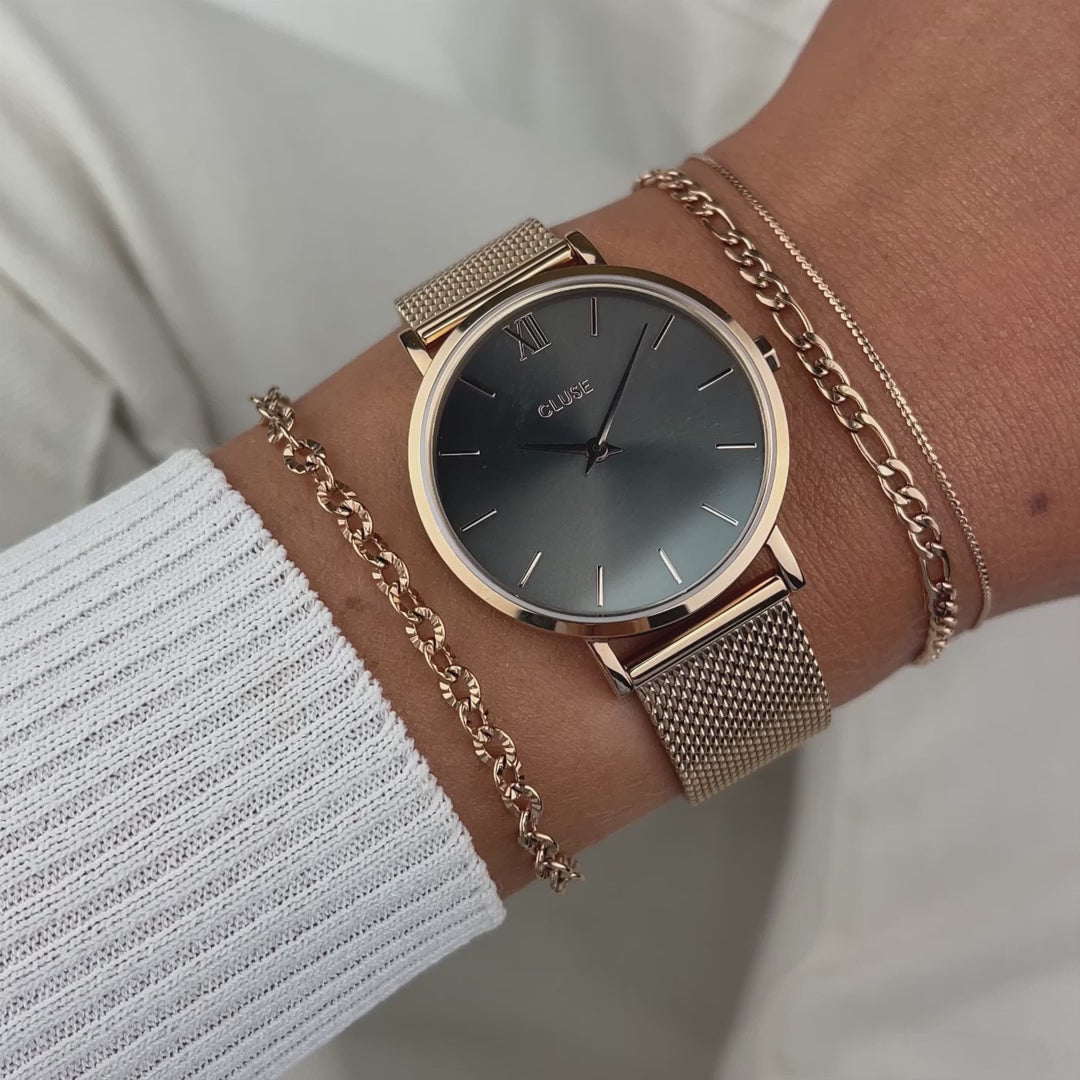 Frau kombiniert die Cluse Stahl-Uhr "Minuit Mesh" in roségoldener Farbe mit einem grau-braunen Zifferblatt mit zwei Armbändern und präsentiert die Uhr per Wrist-Roll der Kamera