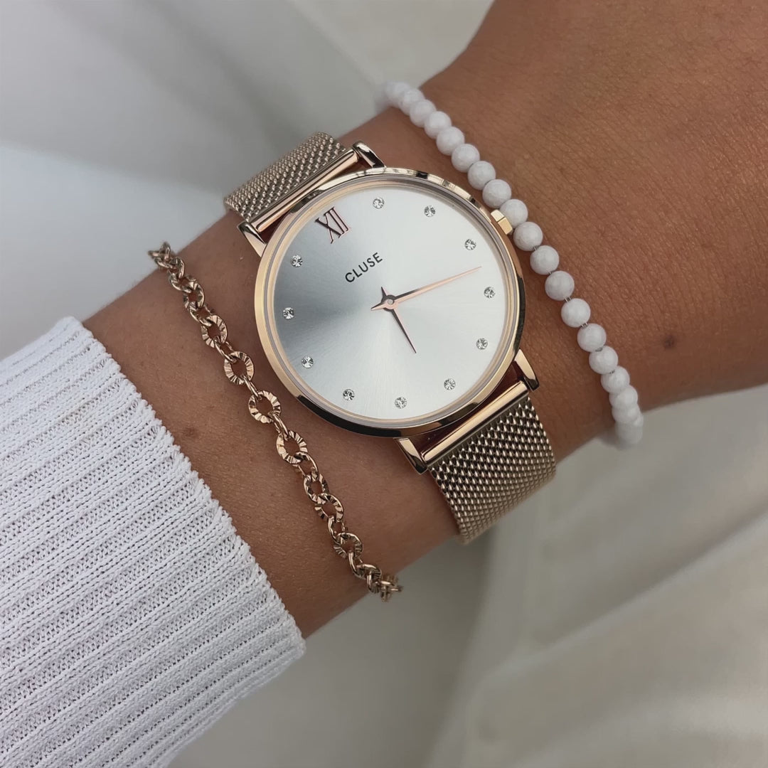 Frau kombiniert die Cluse Stahl-Uhr "Minuir Mesh" in roségoldener Farbe mit einem silbernen Diamant-Zifferblatt mit zwei Armbändern und präsentiert die Uhr per Wrist-Roll der Kamera